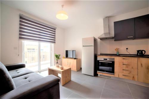a living room with a couch and a kitchen at Elise Apartments in Il-Gżira