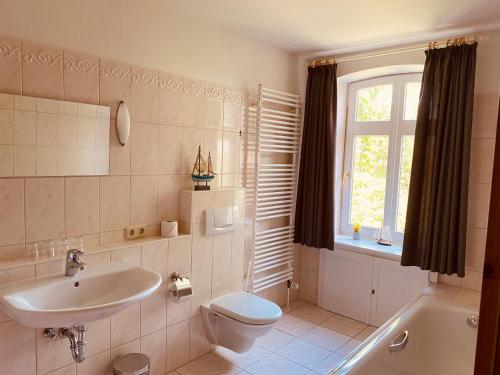 ein Bad mit einem Waschbecken, einem WC und einem Fenster in der Unterkunft Pension Hessbögel in Grünendeich