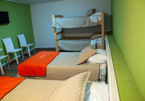 two bunk beds in a green room with chairs at Hostal Casa Alegre in Valparaíso