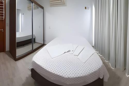 a white bed in a room with a mirror at Apartamento com Vista Única e Maravilhosa !!! in São Vicente