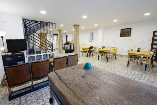 Hostel El Campano في فيلافرانكا ديل بيرزو: غرفة مع طاولة وكراسي وتلفزيون