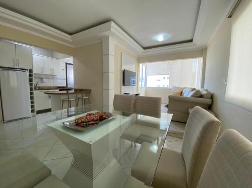 uma cozinha e sala de estar com uma mesa de vidro e cadeiras em Apartamento Beira-Mar em Balneário Camboriú