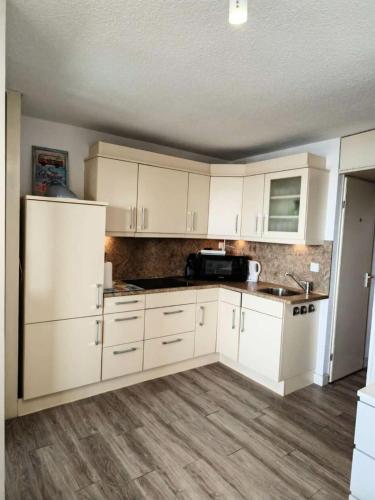 Il comprend une cuisine avec des placards blancs et du parquet. dans l'établissement Résidence Grenada - T2 4 couchages LE BARCARES - climatisé, avec accès internet MAE-0611, au Barcarès