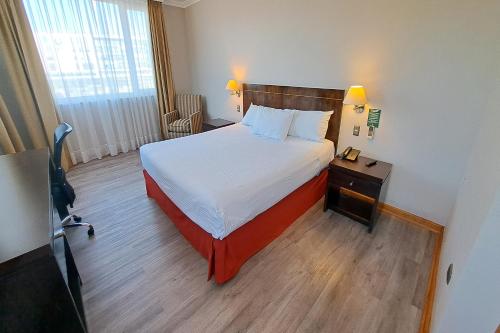 a hotel room with a bed and a night stand at Hotel Diego de Almagro Lomas Verdes in Concepción