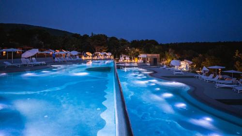 una gran piscina de agua azul por la noche en Adrialux Camping Mobile Homes en Selce