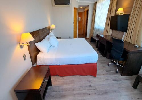 a hotel room with a bed and a desk and a television at Hotel Diego de Almagro Lomas Verdes in Concepción