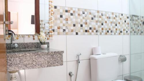 a bathroom with a toilet and a sink and a mirror at Pousada Vila Jesuita in Cairu