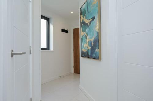 a hallway with a door and a painting on the wall at SoHot Stays Beach Haven Apt With Sea Views A Balcony & Free Parking in Ramsgate