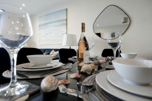 a dining room table with a bottle of wine and glasses at SoHot Stays Beach Haven Apt With Sea Views A Balcony & Free Parking in Ramsgate
