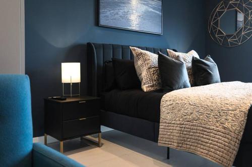 a blue bedroom with a bed with pillows and a lamp at SoHot Stays Beach Haven Apt With Sea Views A Balcony & Free Parking in Ramsgate