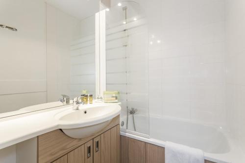 a white bathroom with a sink and a shower at Hôtel Club mmv Les Bergers **** in L'Alpe-d'Huez
