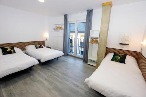 Habitación con 2 camas y sábanas blancas. en Hostel El Campano, en Villafranca del Bierzo