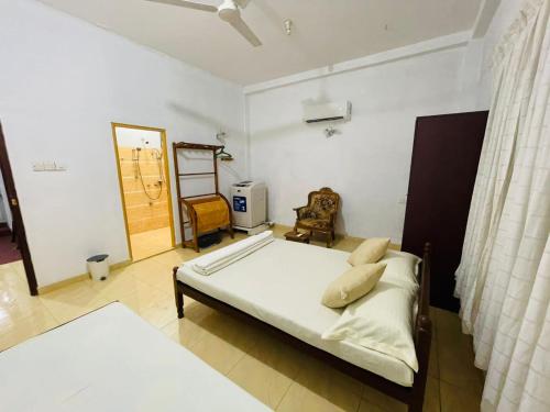 a bedroom with a bed and a chair and a window at Shiv's Villa in Galle