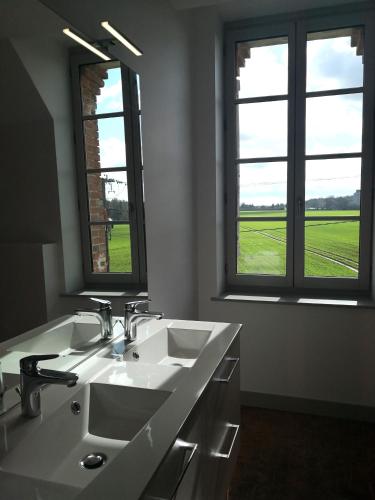 une salle de bain avec deux lavabos et deux fenêtres dans l'établissement Maison La Demi-Lune, à Boulleret