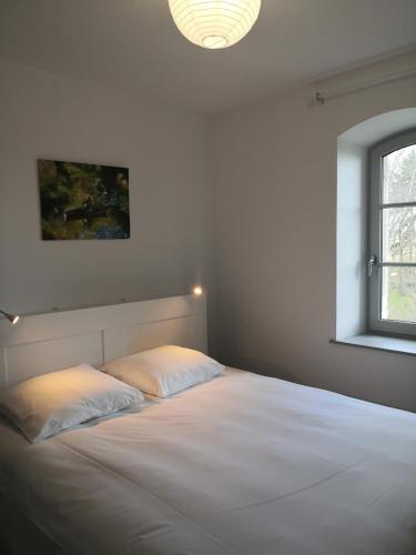 une chambre avec un grand lit blanc avec une fenêtre dans l'établissement Maison La Demi-Lune, à Boulleret