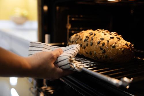 a person is putting a loaf of bread in an oven at La Cochera Casa Emblemática en Santa Cruz de Tenerife in Santa Cruz de Tenerife