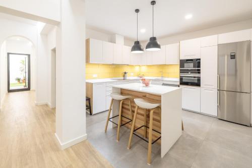a kitchen with white cabinets and a island with bar stools at La Cochera Casa Emblemática en Santa Cruz de Tenerife in Santa Cruz de Tenerife