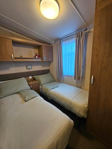 a room with three beds and a window at Oak Green- Top award winning caravan! in Gristhorpe