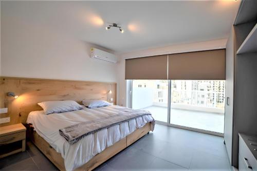 sypialnia z dużym łóżkiem i dużym oknem w obiekcie Elise Apartments w Gżirze