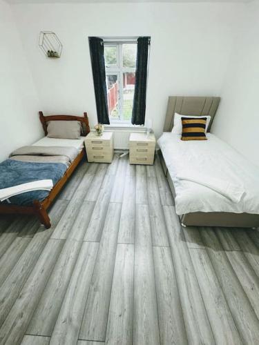 a bedroom with two beds and a wooden floor at SwankyHome4Groups/Contractors/M5 in Dudley