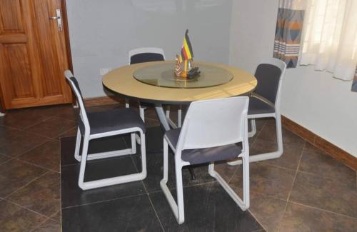 a dining room table with chairs and a table with a lamp at Migingo Suites in Entebbe