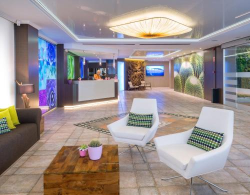 un vestíbulo con 2 sillas blancas y un sofá en Hotel Kaktus Playa - Adults Recommended, en Calella