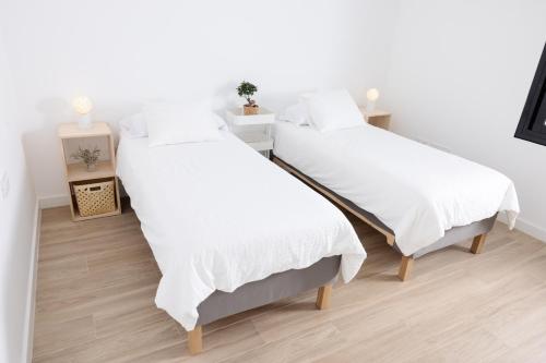 two beds in a room with white sheets at Piso de lujo en Tenerife La Cochera in Santa Cruz de Tenerife