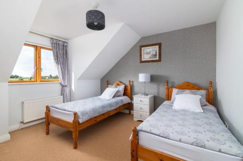 a bedroom with two beds and a window at Shannonside - Stylish 5 Bed Marina home & 40ft mooring in Termonbarry