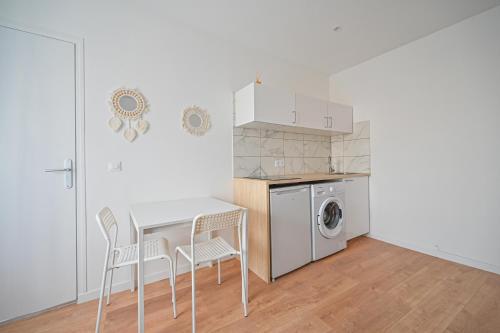 une cuisine avec une table et des chaises ainsi qu'un lave-linge dans l'établissement Appartement cosy, neuf et tout equipé, à 3mn à pied de Paris, à Clichy