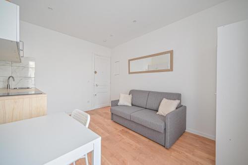 un salon avec un canapé et une cuisine dans l'établissement Appartement cosy, neuf et tout equipé, à 3mn à pied de Paris, à Clichy