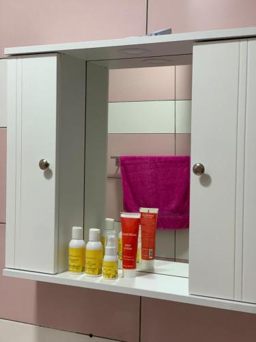 a shelf with bottles of oils and a mirror at Ridi's Comfort Apartment 2 in Shkodër