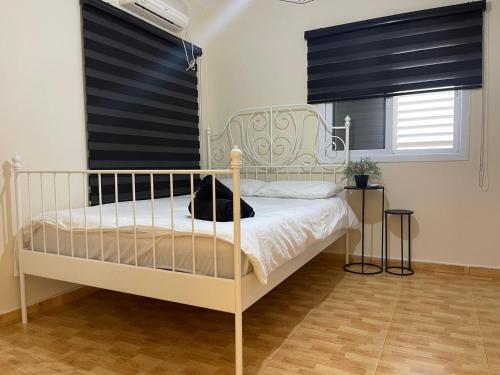 um quarto com uma cama branca e cortinas pretas em וילת אבן ספיר em Gefen