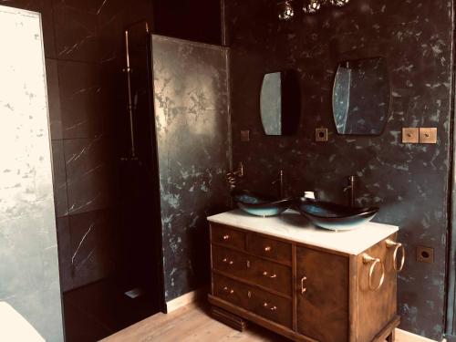 a bathroom with two sinks and a black wall at L'ancien Mystic ManOir DeDame in Ventron