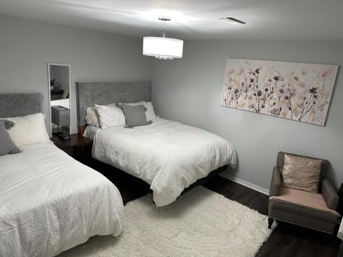 um quarto com 2 camas e uma cadeira em Luxurious and modern one bedroom basement suite. em Brampton
