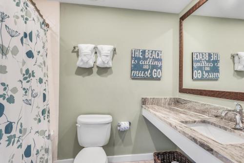 a bathroom with a toilet and a sink and a mirror at Luau I 7905 Studio in Destin