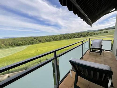 balcón con silla y vistas a un campo de golf en Mirador Rioja alta golf, en Cirueña