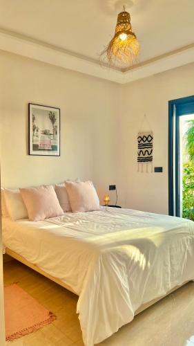 a large white bed in a bedroom with a chandelier at Cozy 2 bedrooms flat at Dar Bouazza in Dar Bouazza