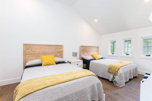 2 camas en un dormitorio con paredes blancas y suelo de madera en The Pool House at Fr. Sorin's w/ Paddle Tennis, en South Bend