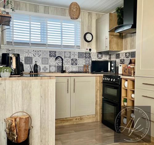 a kitchen with white cabinets and black appliances at Coastal Lodge cherry park chapel st Leonards Skegness in Skegness