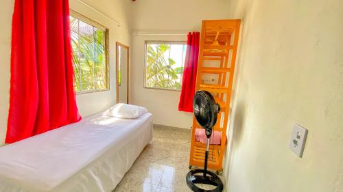 a bedroom with red curtains and a bed with a fan at Lar Lalunalê 3 in Prado
