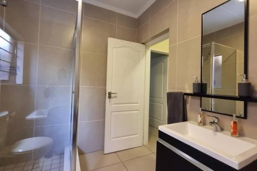 a bathroom with a sink and a shower with a door at Home Away From Home in Midrand