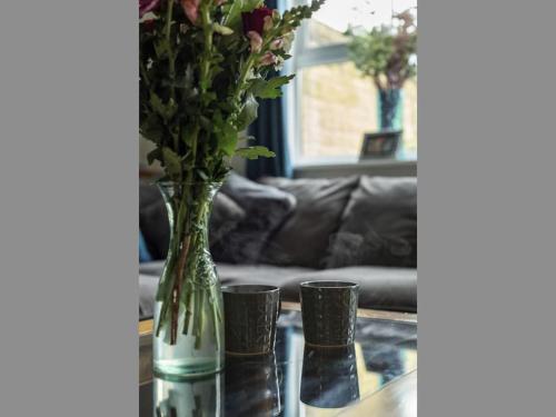 a vase with flowers on a table with two cups at The Case in Point in Witney