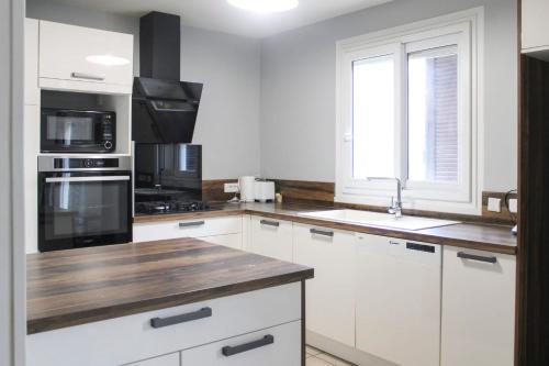 uma cozinha com armários brancos e um balcão de madeira em Cozy and spacious house in Saint-Denis em Saint-Denis