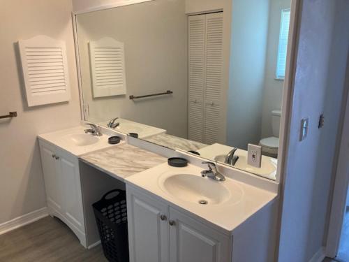a bathroom with two sinks and a large mirror at Sebastian Gardens Inn & Suites in Sebastian