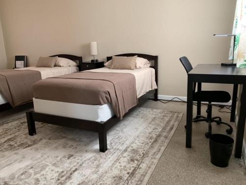 a bedroom with two beds and a desk and a table at Sebastian Gardens Inn & Suites in Sebastian