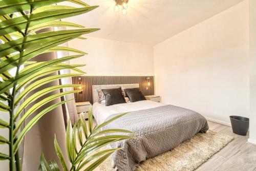 ein Schlafzimmer mit einem Bett und einer großen Pflanze in der Unterkunft Stylish 1BR Apartment - Parking - Netflix in Walsall