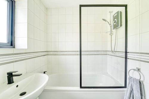La salle de bains blanche est pourvue d'une baignoire et d'un lavabo. dans l'établissement Stylish 1BR Apartment - Parking - Netflix, à Walsall
