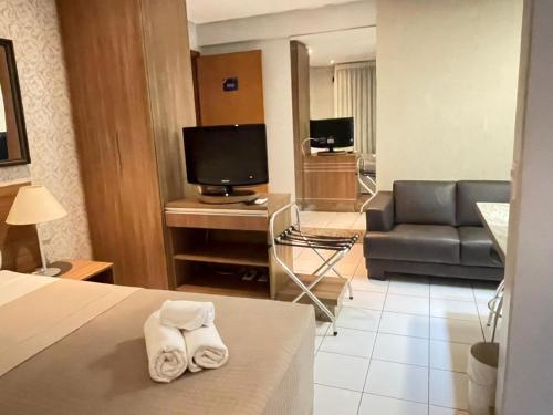 a hotel room with a bed and a living room at Sun Square Suítes Hotel By Lual in Goiânia