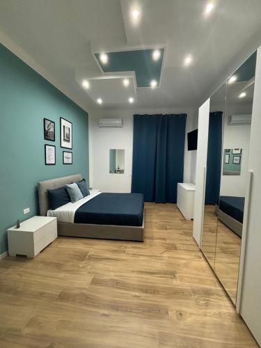 um quarto com uma cama, paredes azuis e pisos em madeira em Salotto Mariella em Nápoles