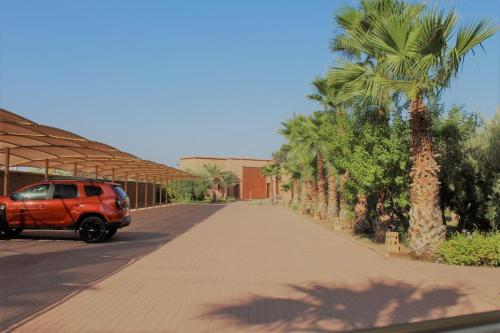 a red van parked on a street with palm trees at Domaine Casa Cecilia in Marrakech